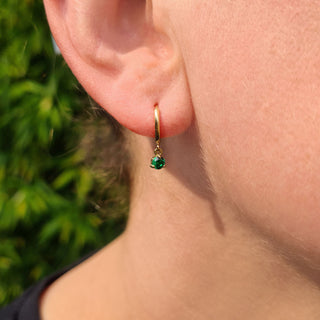 emerald huggie earrings in ear