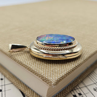 A solid gold locket set with a black opal triplet