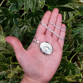 locket necklace in hand for scale
