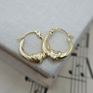 9ct yellow gold mini creole hoop earrings with puffed heart detail displayed on grey linen cushion