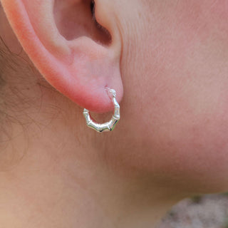 silver creole earrings in ear