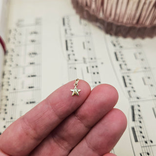 gold star charm in hand for scale