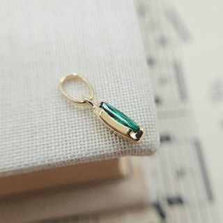 solid gold charm set with emerald green gem