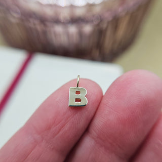 tiny B charm on finger tip for scale