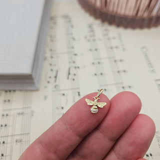 dainty 9ct gold bee charm in hand for scale