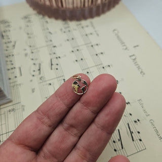gold earth charm in hand for scale