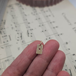 very small gold tag in hand for scale