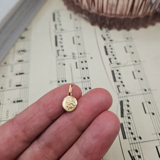 tiny solid gold st christopher charm in hand for scale