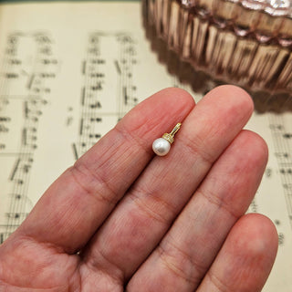pearl charm in hand for scale