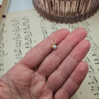 9ct gold shell charm in hand for scale