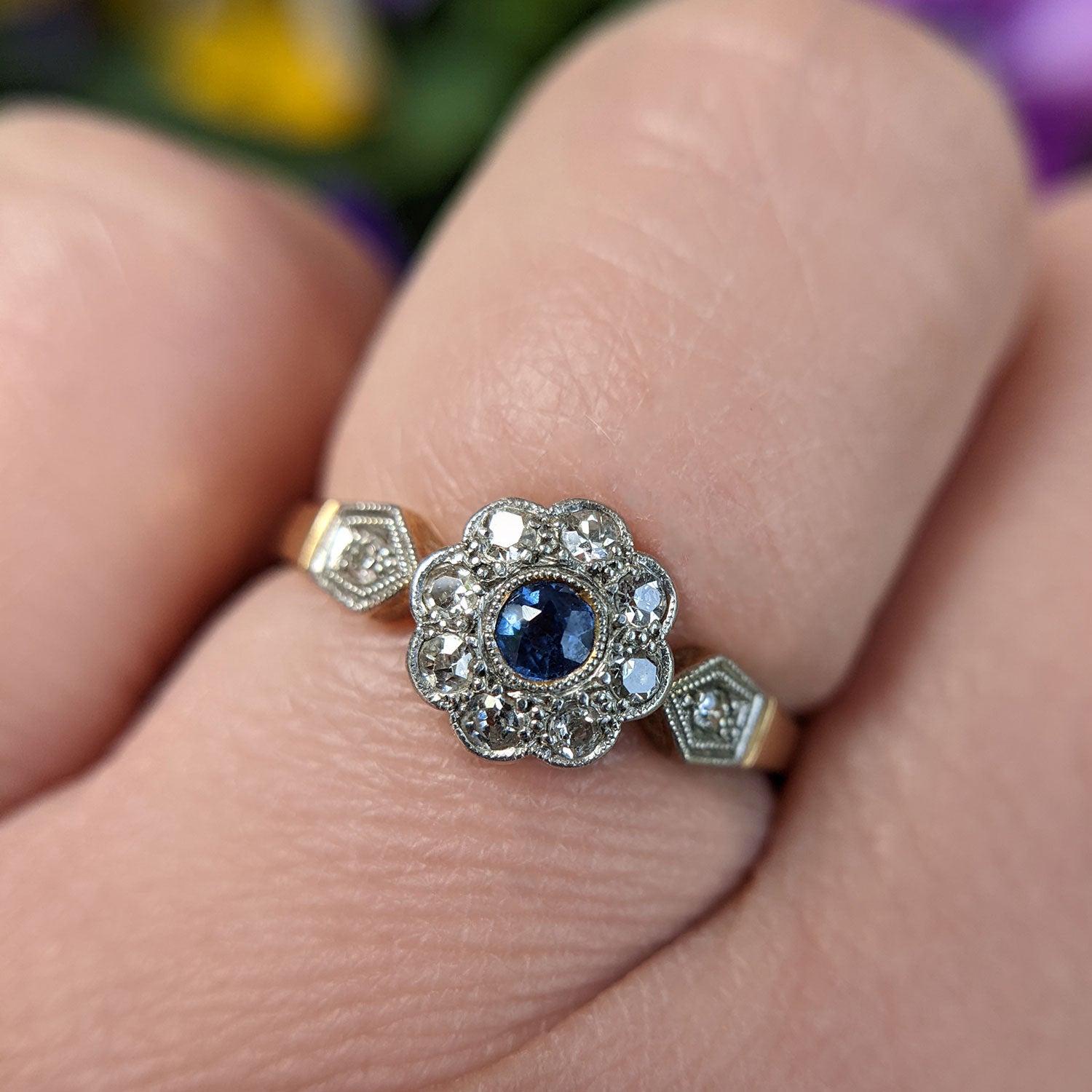 close up of Edwardian sapphire flower ring on finger