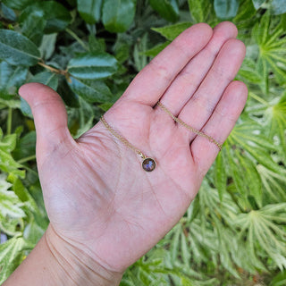 dainty labradorite pendant in hand for scale