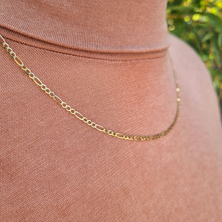 close up of women's gold figaro chain