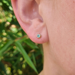 very small emerald studs in ear