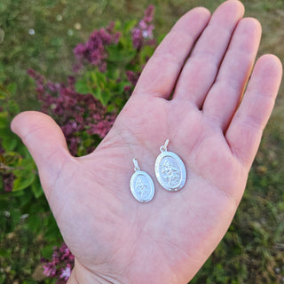 oval st christopher pendants in hand for scale