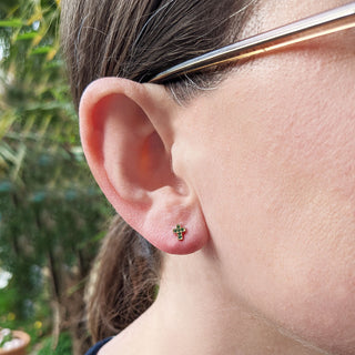 very small cross earrings in emeralds in ladies ear