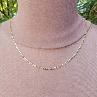 gold figaro chain being worn