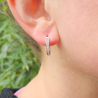 white huggie earrings in ear