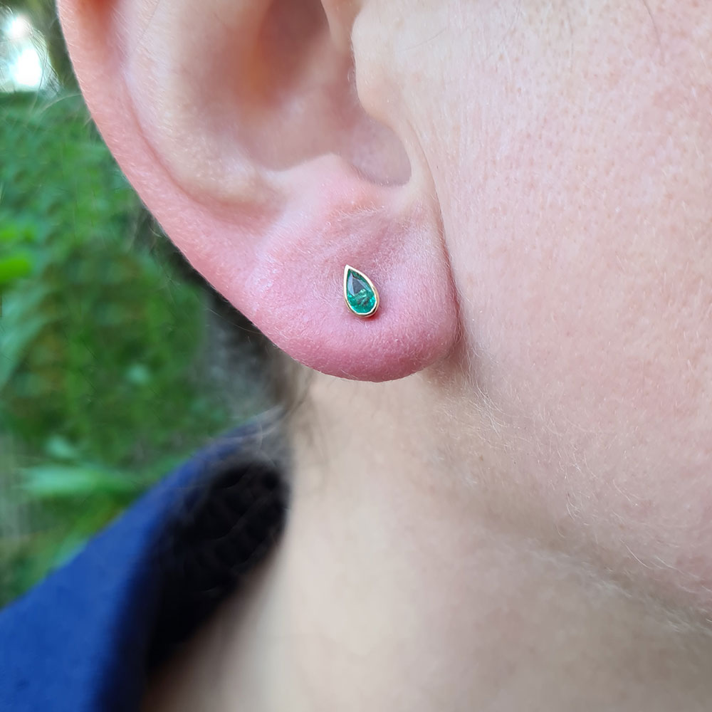 dainty emerald pear studs in ear