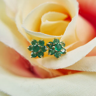 dainty flower stud earrings with green emeralds