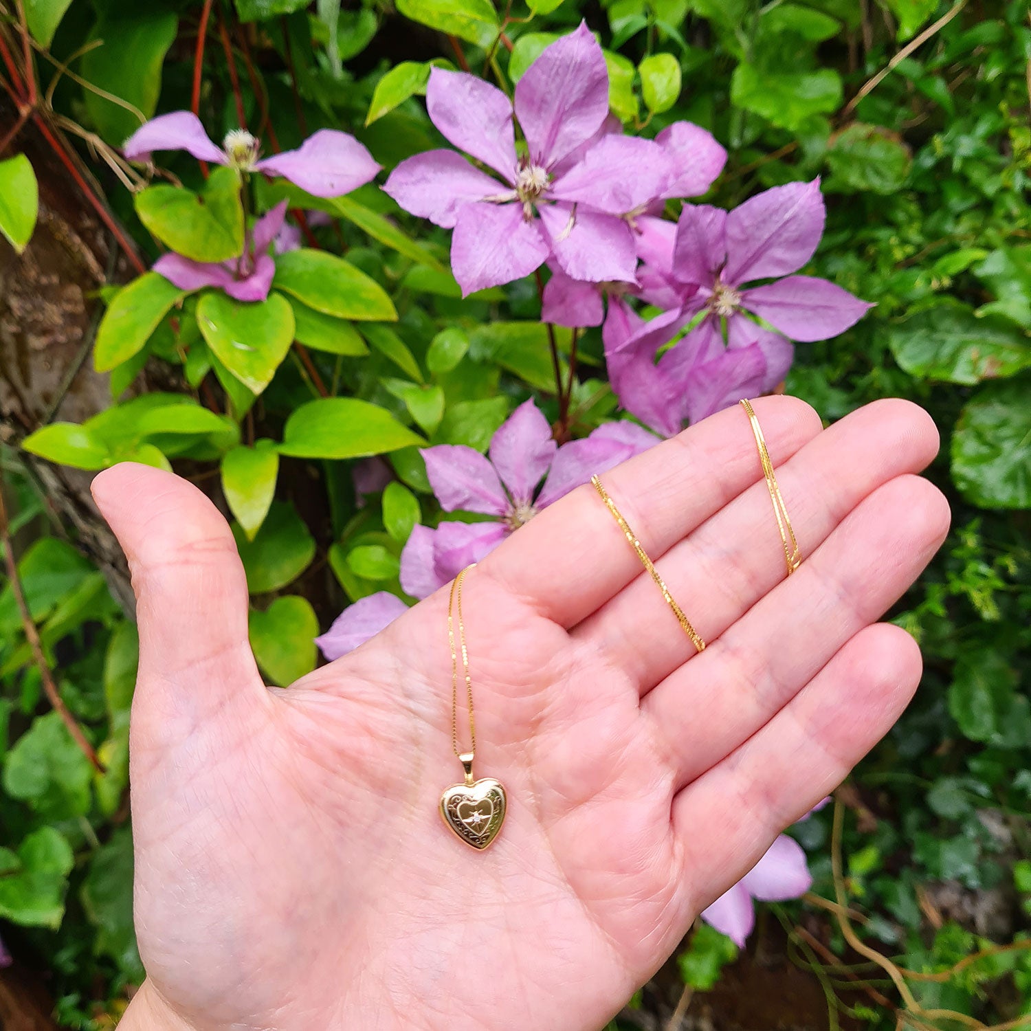 small gold heart locket in hand for scale