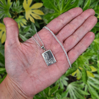 silver book locket in hand for scale