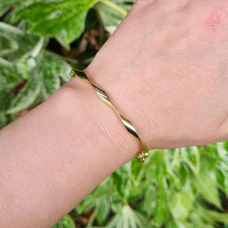 yellow gold twist bangle on ladies wrist