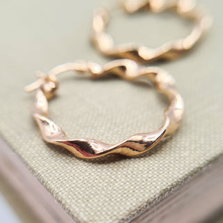 close up of gold twisted hoop earrings