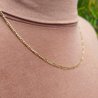 close up of solid gold figaro chain