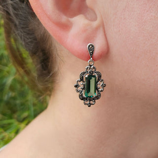 green gem dangle earrings in woman's ear