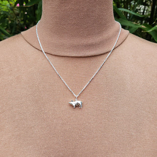 view of pig charm necklace in silver being worn