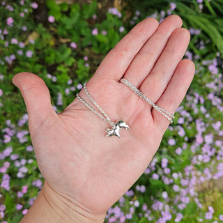 silver pig charm in hand for scale