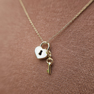 close up of gold padlock and key charm pendant