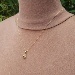 gold knot pendant and chain being worn