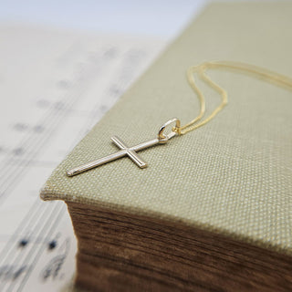 close up of gold skinny cross pendant