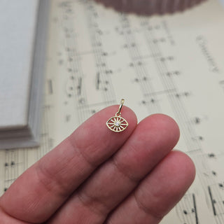 small gold eye charm in hand for scale