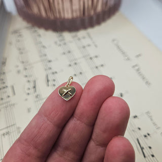 gold heart charm in hand for scale
