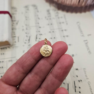 gold st chris charm in hand for scale