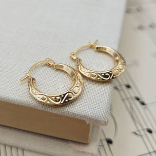 small gold creoles with an engraved design