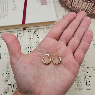 gold creoles in hand for scale