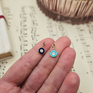 gold evil eye charms in hand for scale