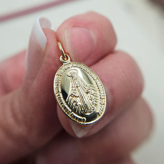 gold Miraculous in hand for scale