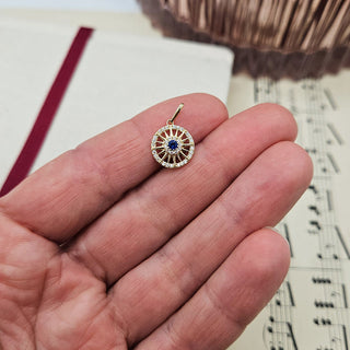 gold sunburst pendant in hand for scale
