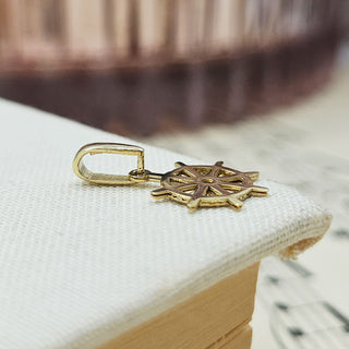 wide view of small gold ship's wheel charm