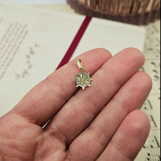 gold charm in hand for scale