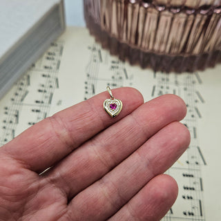 gold heart charm in hand for scale