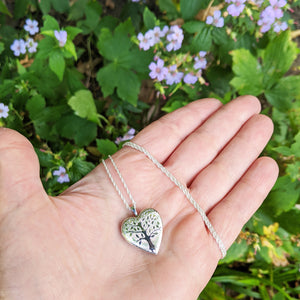 silver heart locket in hand for scale