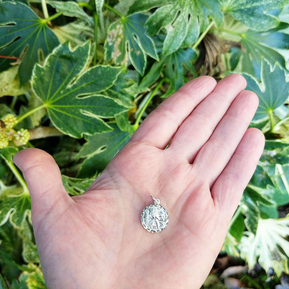 children's st christopher pendant in hand for scale