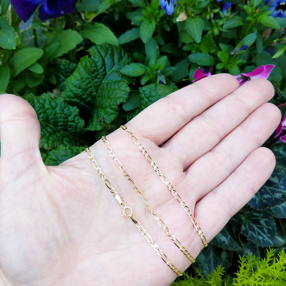 gold figaro chain in hand for scale
