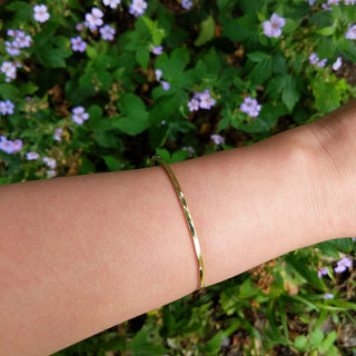 gold torque bangle on wrist